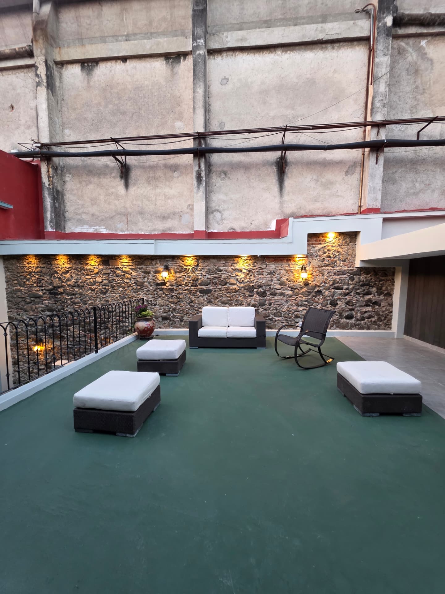 Terraza del edificio con sala exterior y muro de piedra iluminado